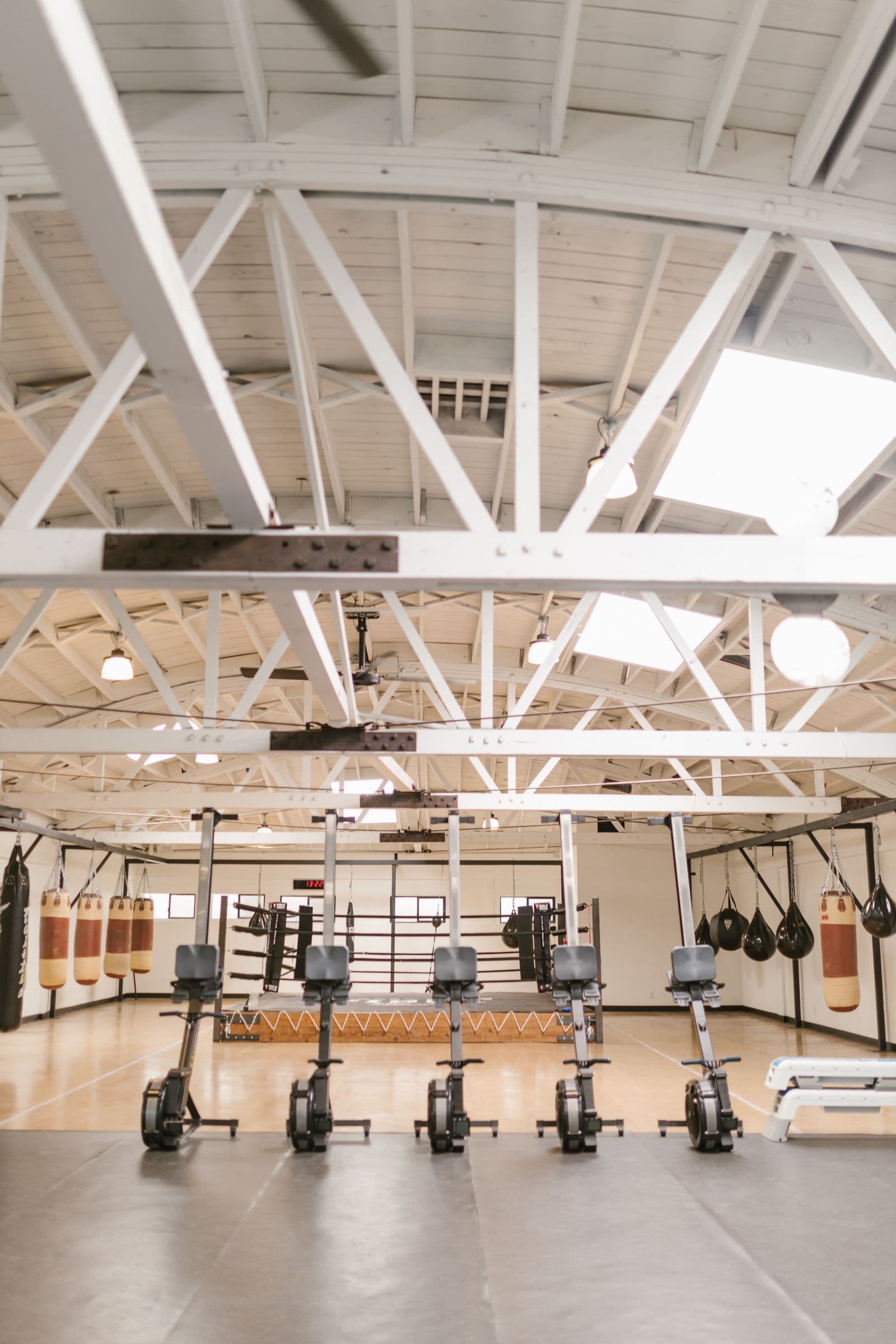 Academia com sacos de boxe, ringue e equipamentos de treino