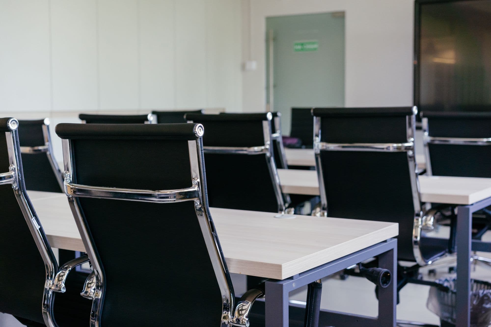 Sala de reunião com cadeiras pretas e mesas brancas em escritório moderno