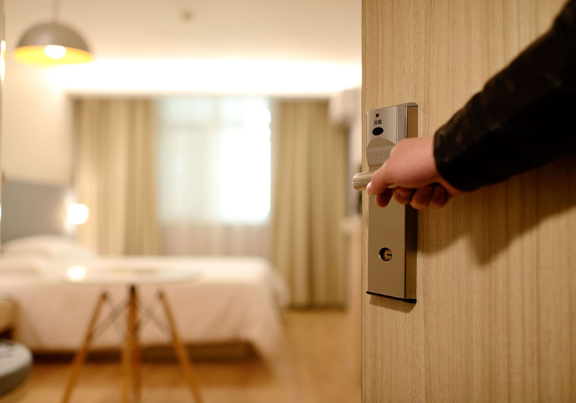 Entrada de quarto de hotel com iluminação acolhedora e porta aberta para a suíte