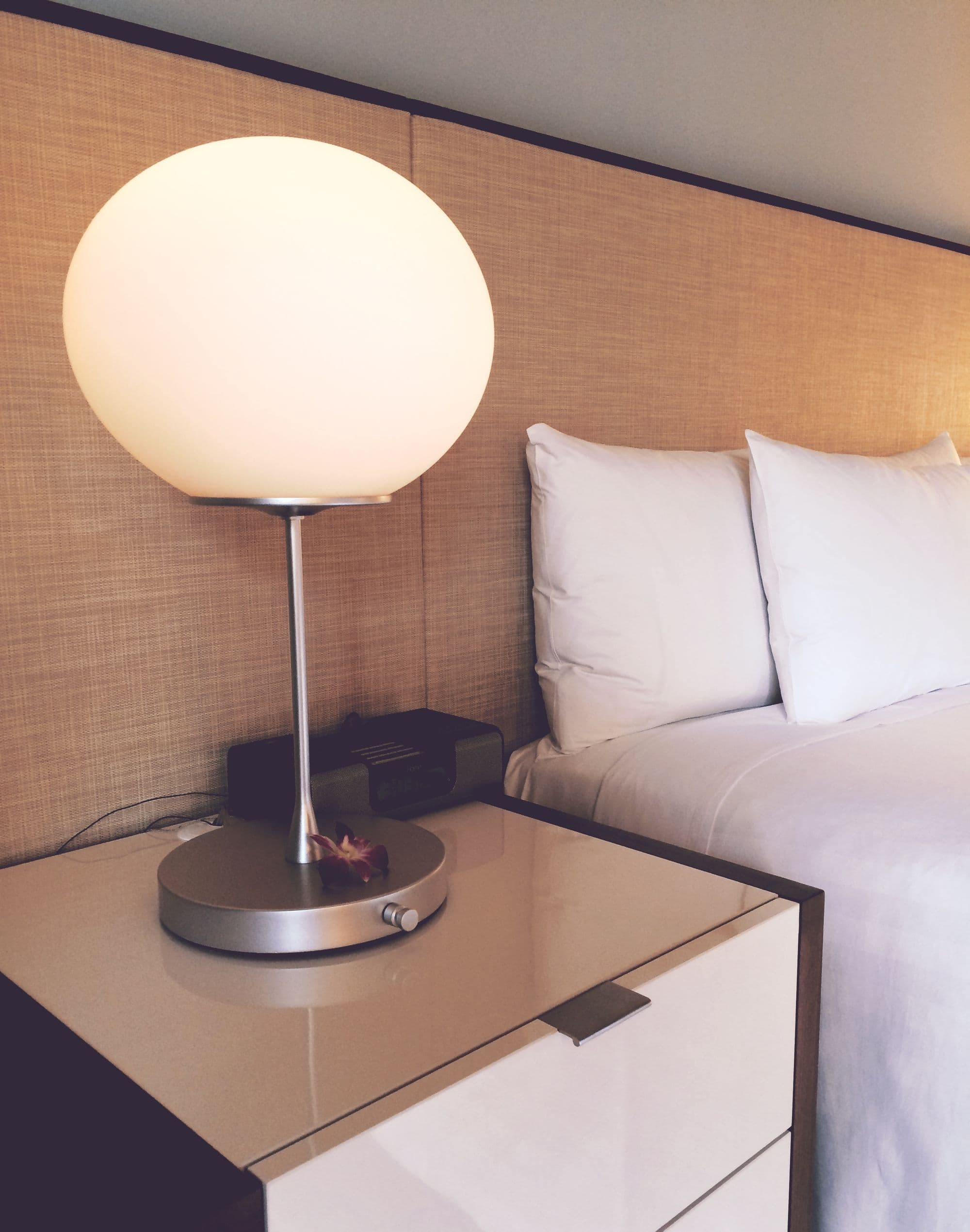 Suíte de hotel com cama arrumada, iluminação suave e mobiliário contemporâneo