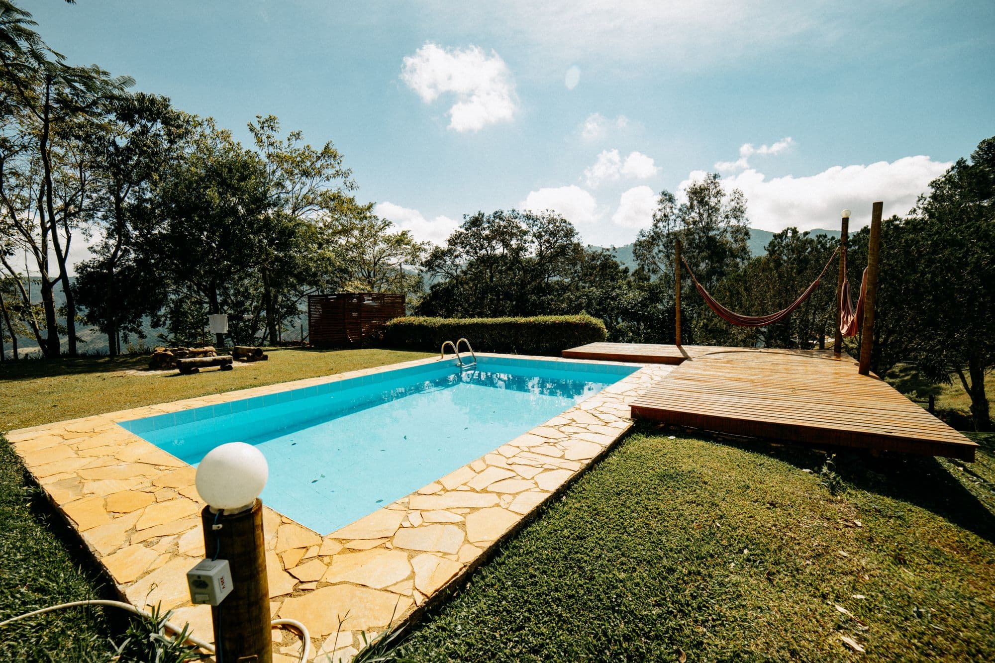 Área de lazer com piscina, palmeiras e espreguiçadeiras